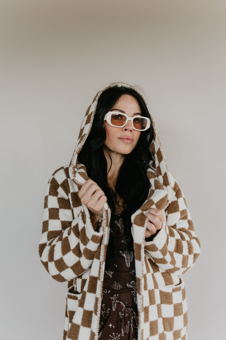 a woman wearing a checkered coat and sunglasses