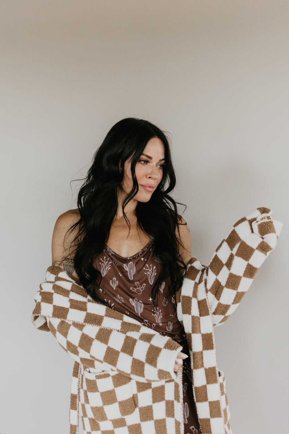 a woman with long hair wearing a brown and white checkered blanket