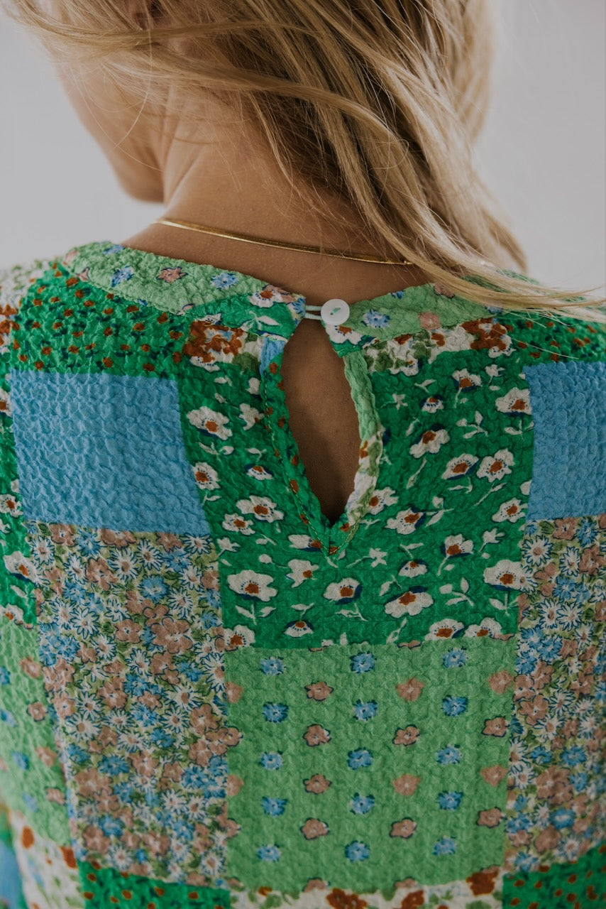 a woman wearing a green shirt with a patchwork pattern