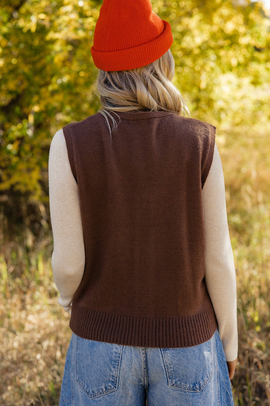 a woman wearing a brown vest and orange hat