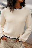 Person wearing a cream sweater with blue trim in an outdoor setting