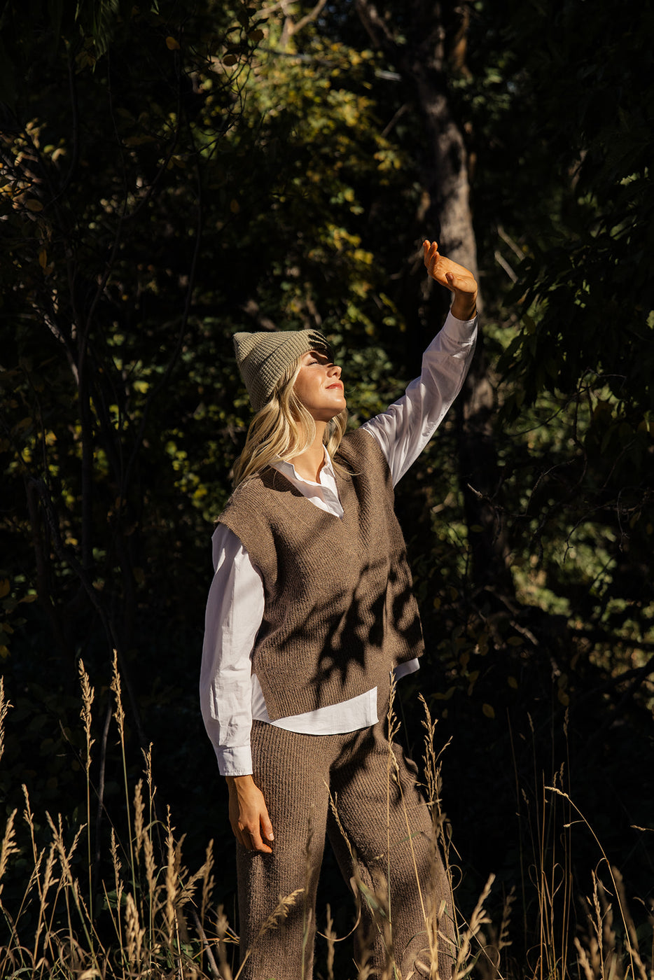 a woman in a hat and vest standing in a field