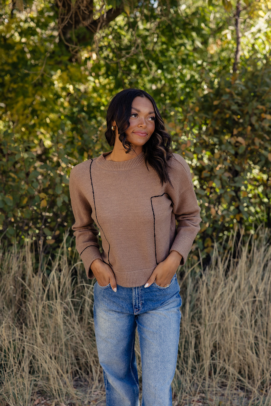 a woman standing in front of tall grass