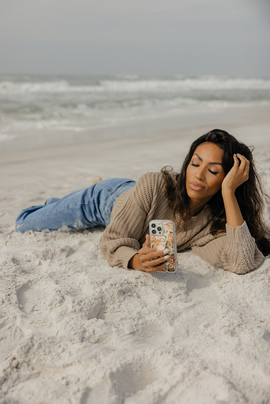 a woman lying on the sand taking a selfie