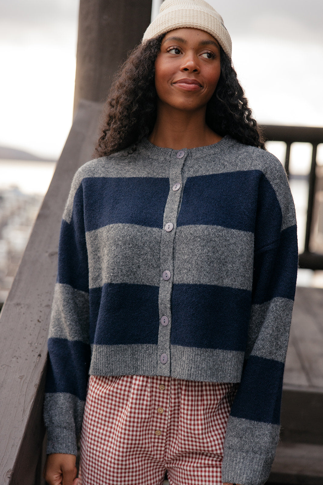 Woman wearing a blue and gray striped sweater with plaid pants, standing outdoors.