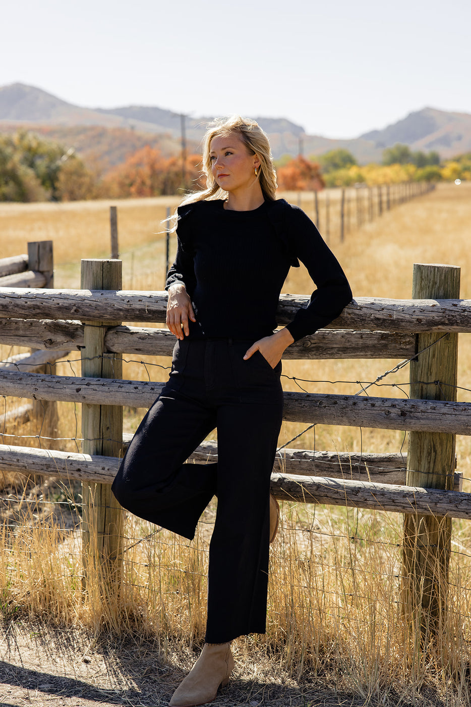 a woman leaning against a fence