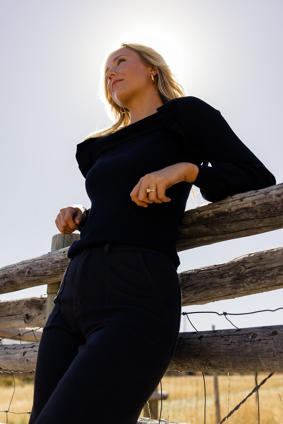 a woman leaning on a wooden fence