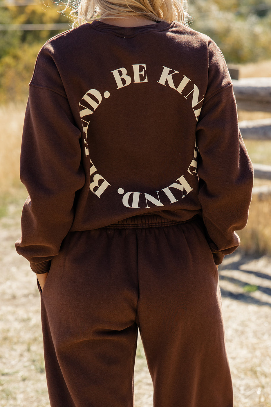 a person wearing a brown sweatshirt with white text on the back