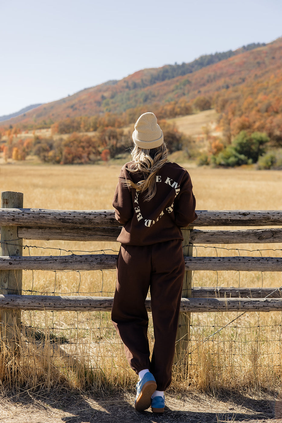 a woman standing by a fence