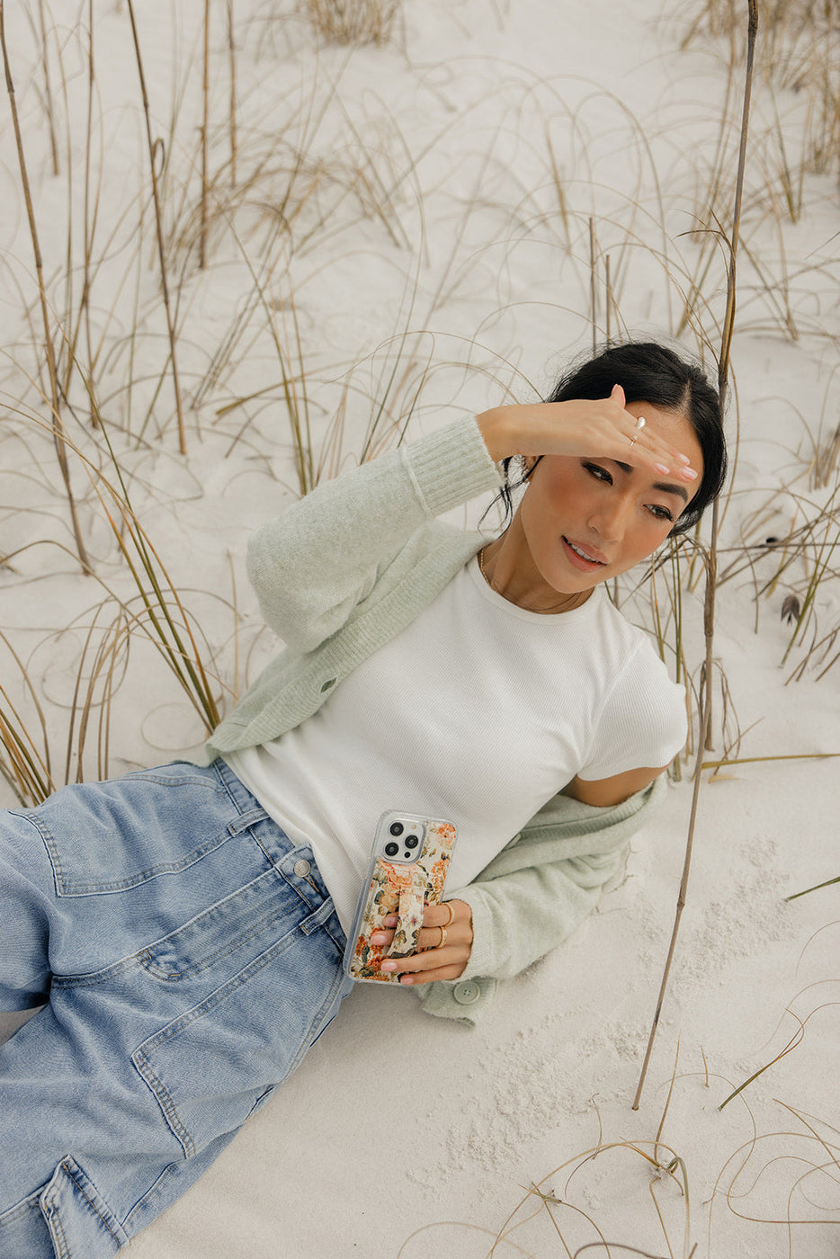 a woman sitting in the snow holding a phone and a case