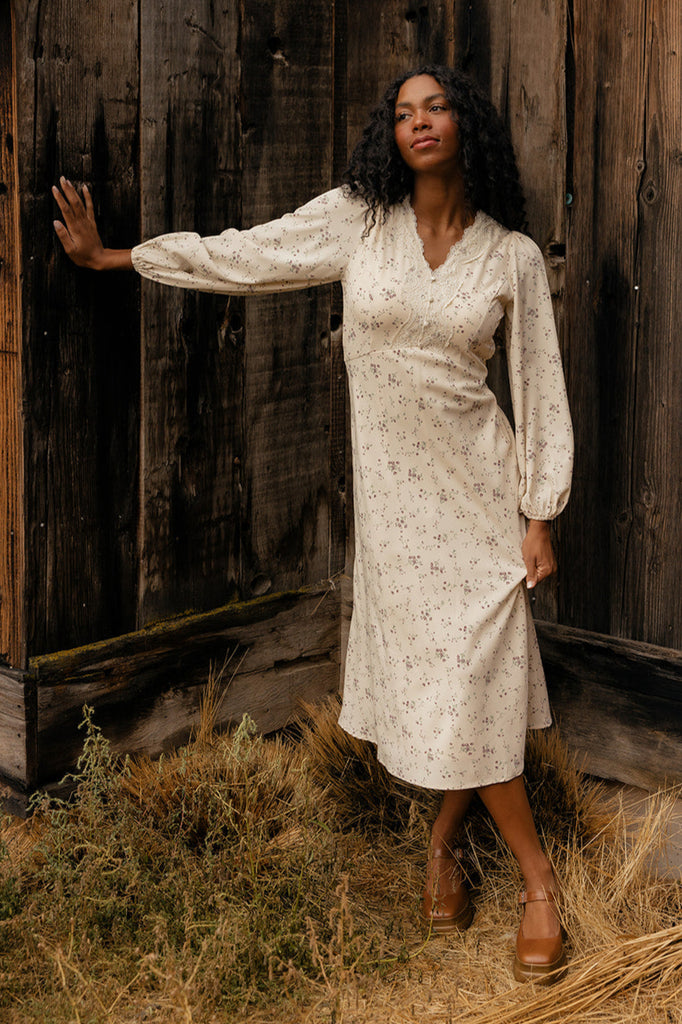 Woman in a white dress standing in front of a wooden building