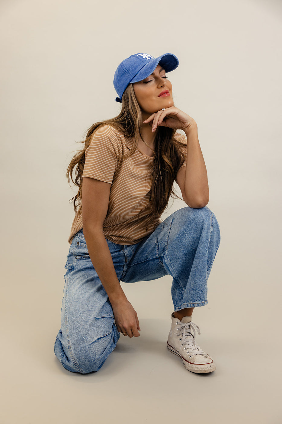 a woman in a hat and jeans squatting