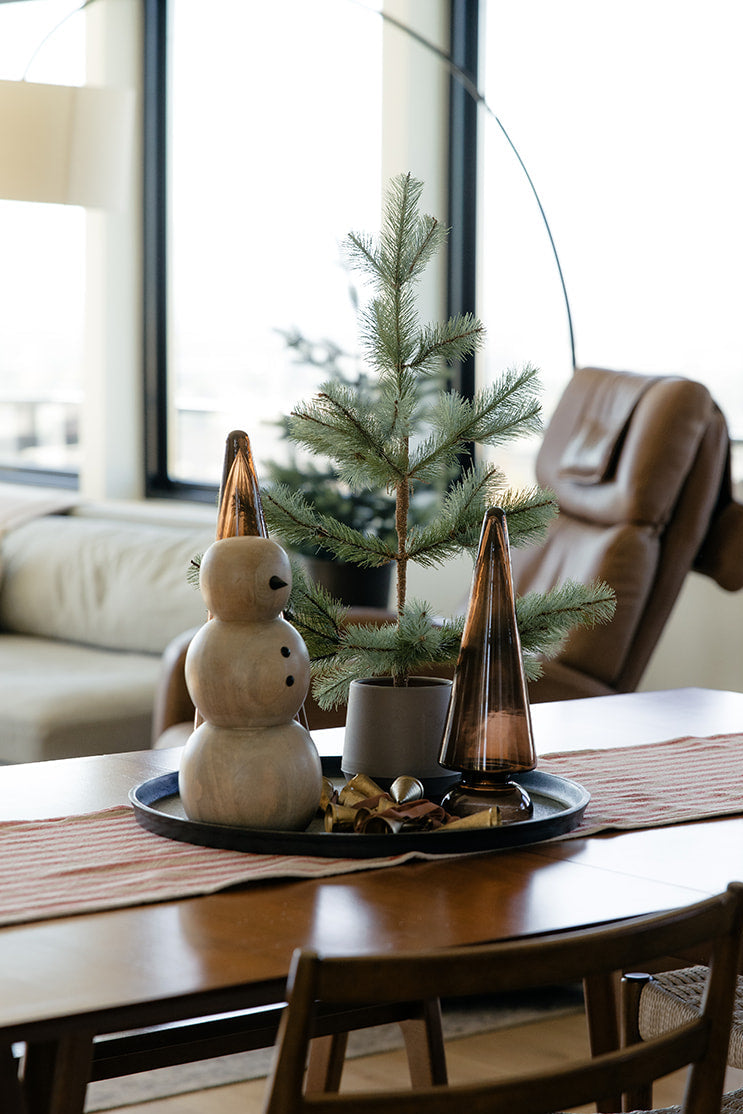 Dining room with a table set for Christmas, featuring a small tree and decorative items.
