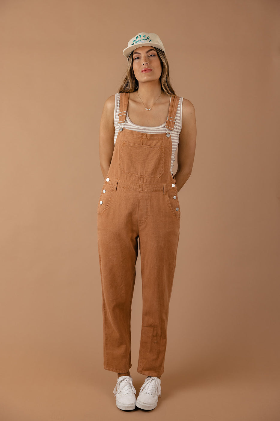 a woman in overalls standing in front of a wall