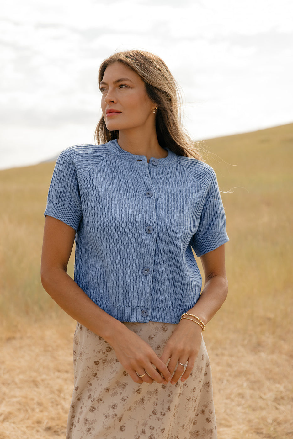 Woman wearing a blue short-sleeve shirt standing in a desert-like landscape