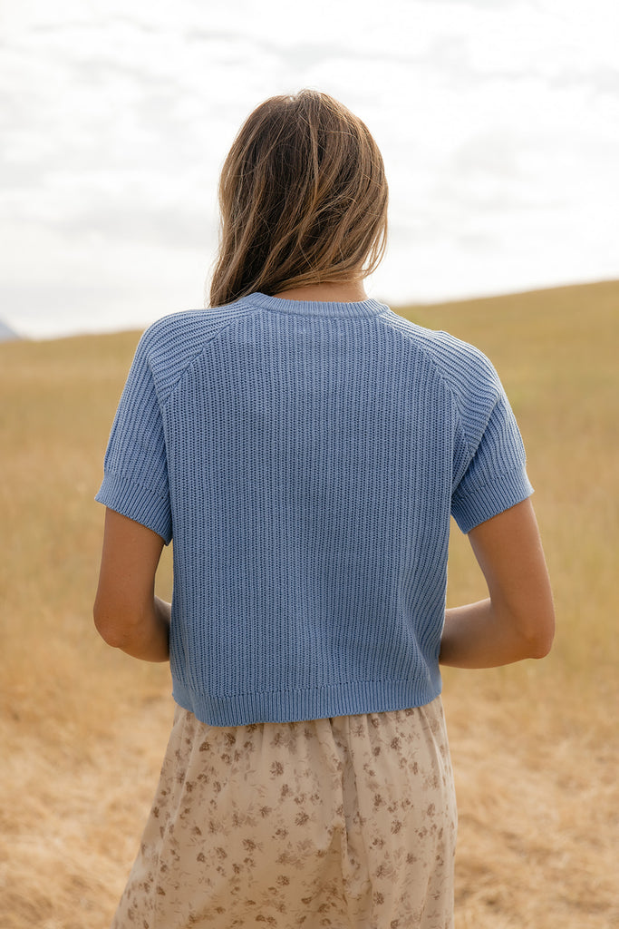 Person wearing a blue ribbed sweater in a desert setting