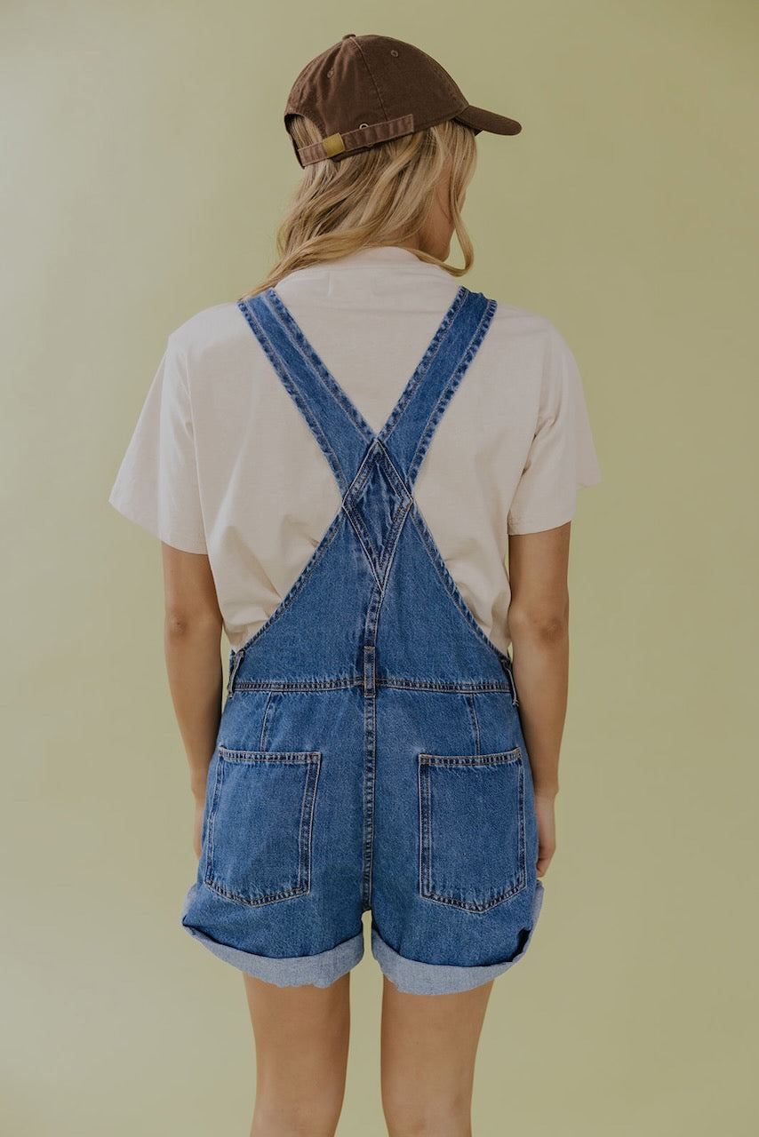 a woman in a white shirt and blue overalls