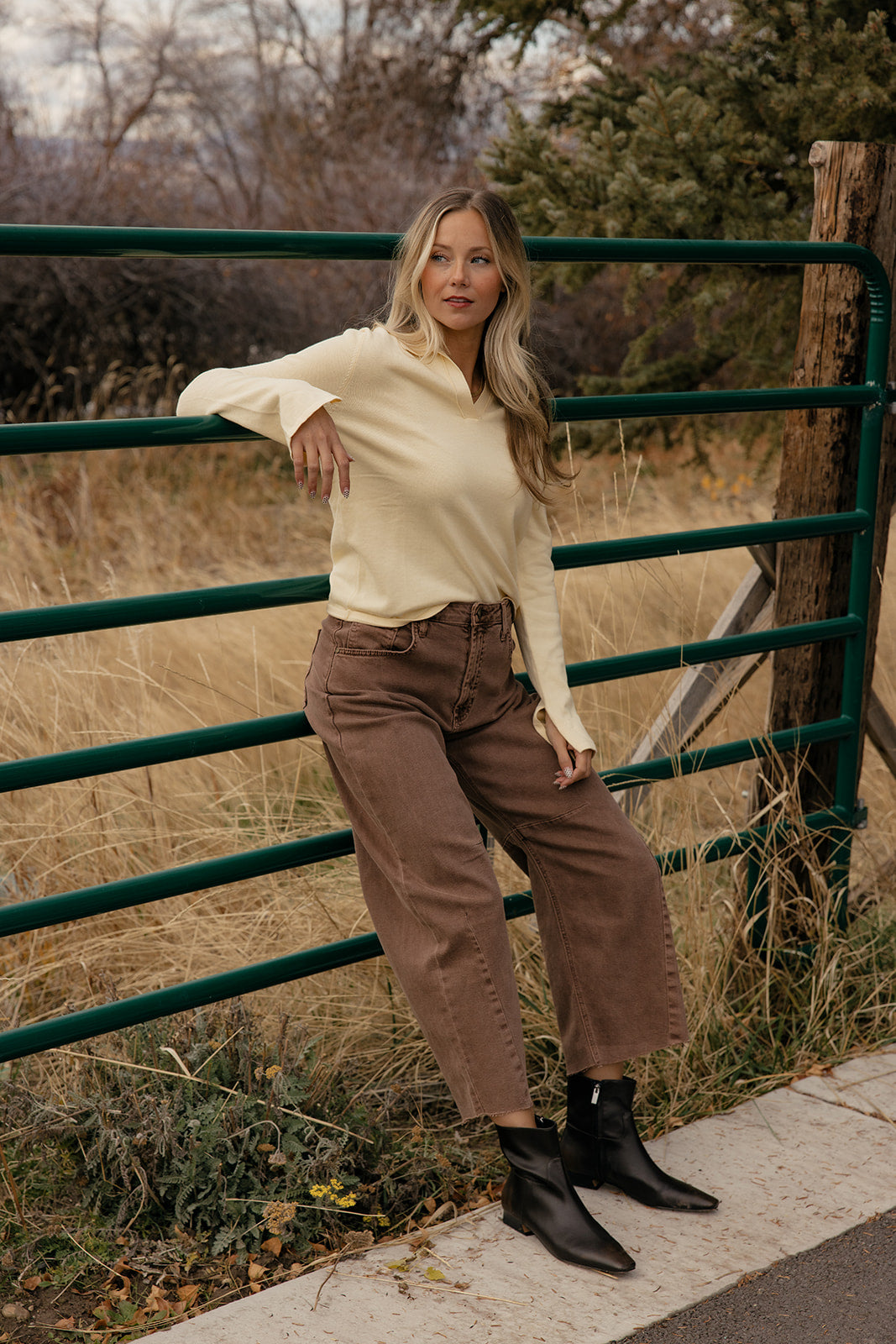 Woman standing by a green metal gate in a natural setting