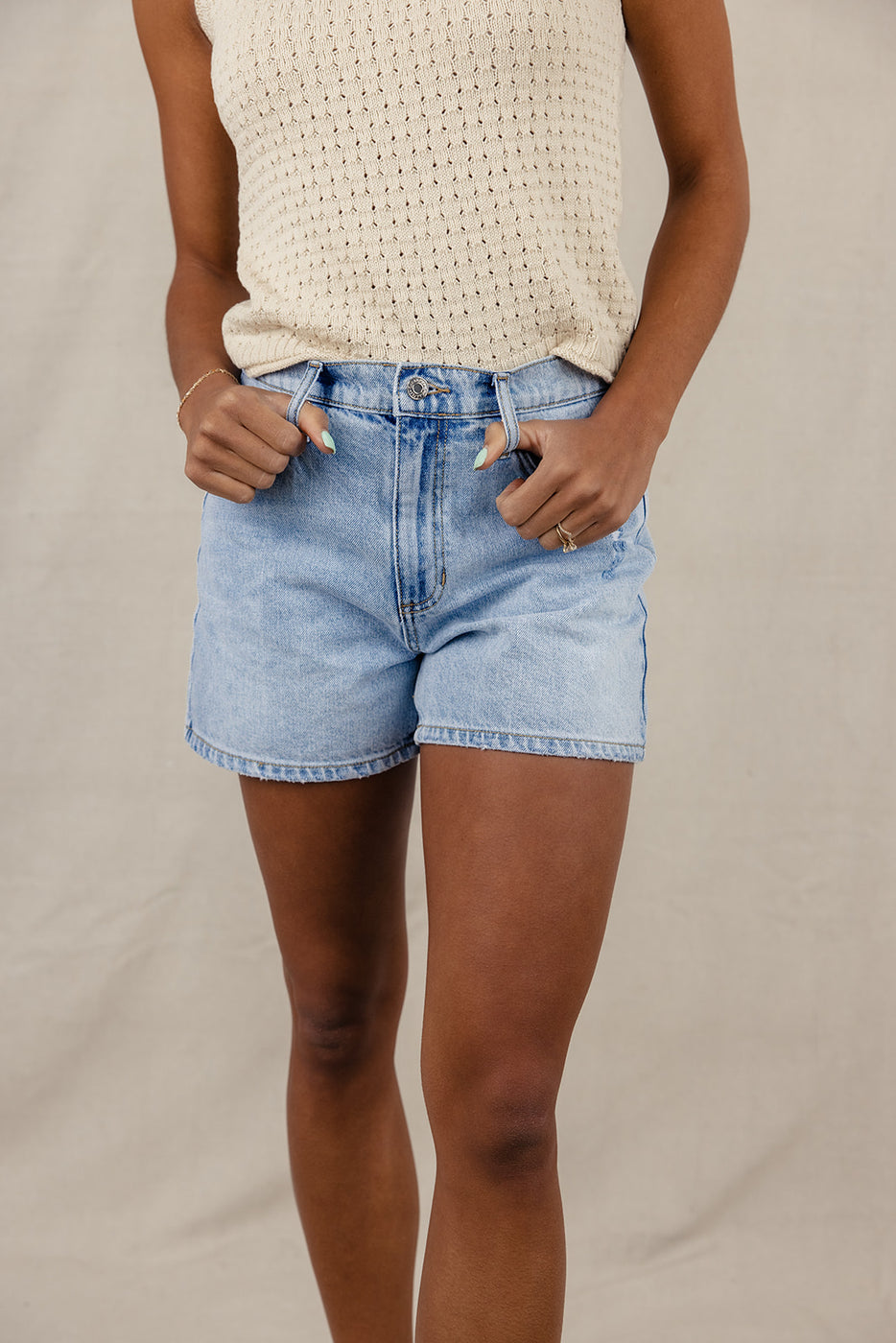 a woman wearing shorts and a beige tank top