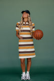Woman in a striped dress holding a basketball against a green background