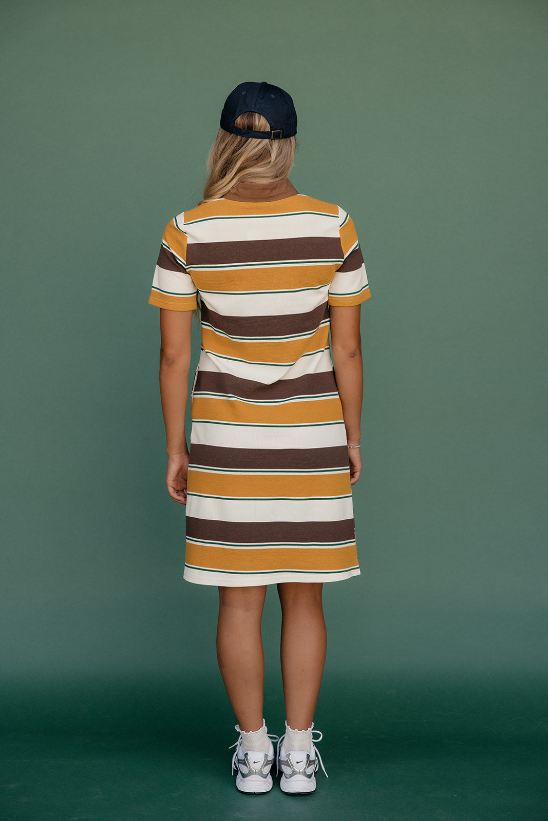 Person wearing a striped dress with a green background