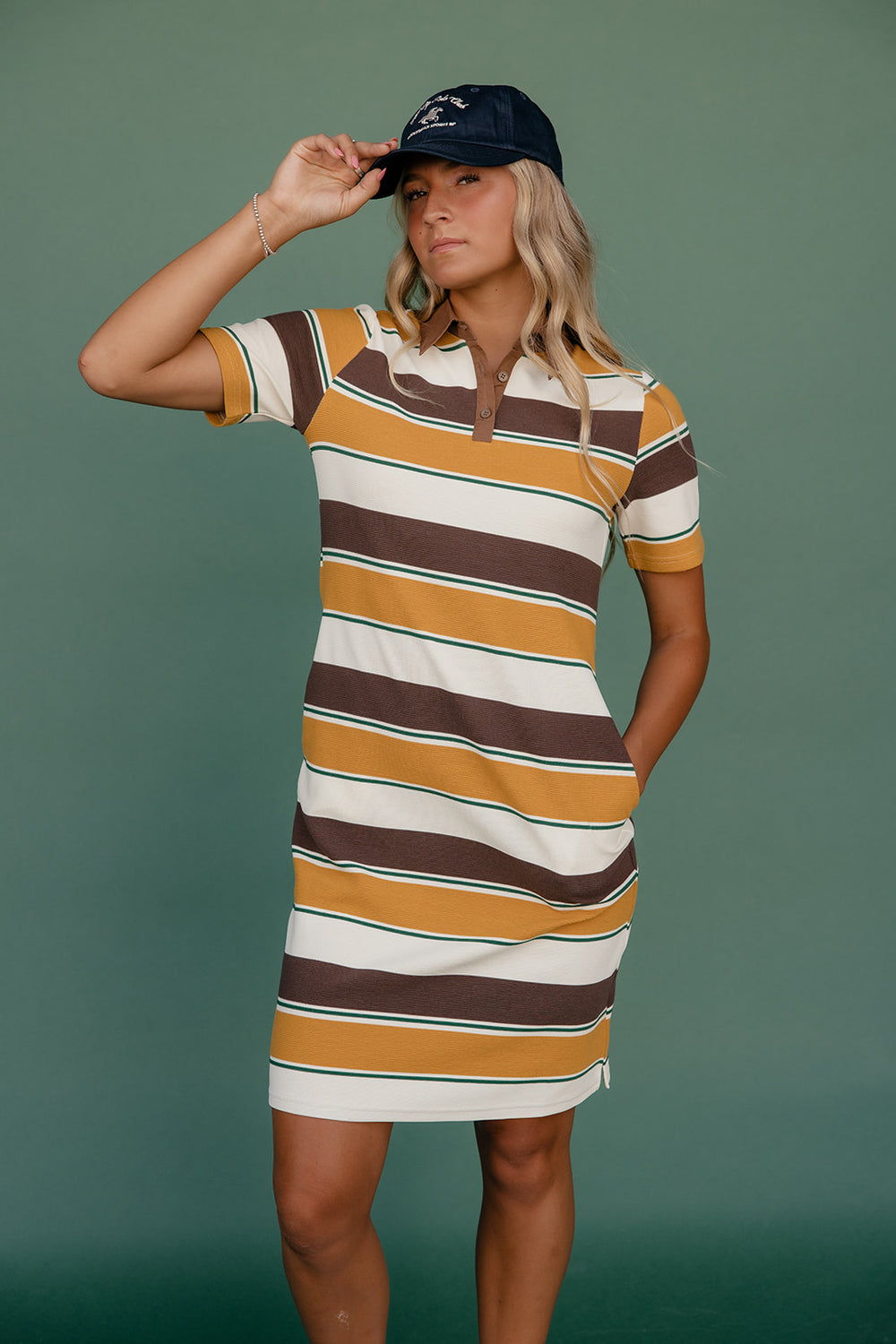 Woman wearing a striped dress and cap against a green background