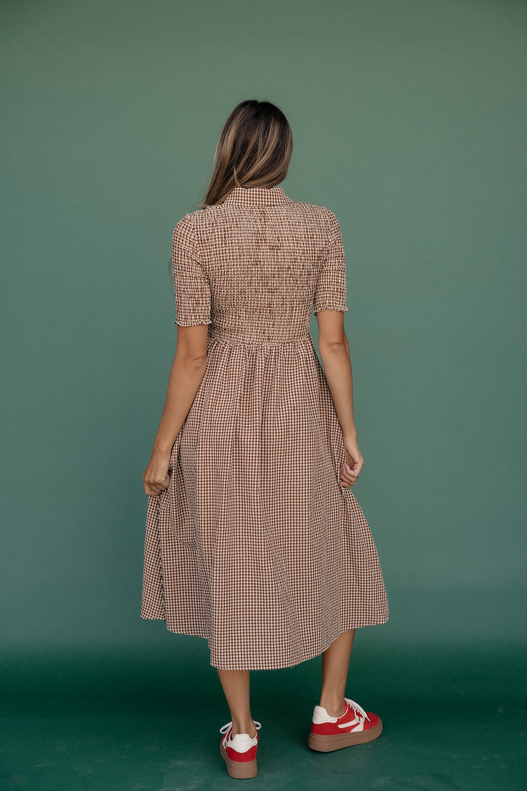 Woman wearing a checkered dress on a green background