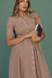 Woman wearing a brown checkered dress holding a book against a green background