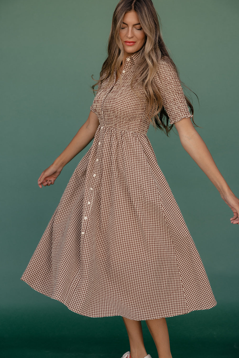 Woman wearing a brown checkered dress against a green background