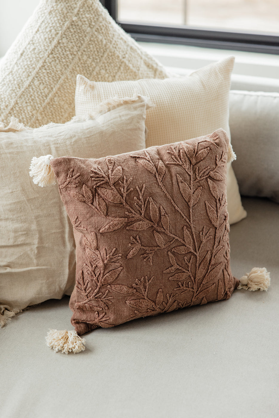 a brown pillow with tassels on it
