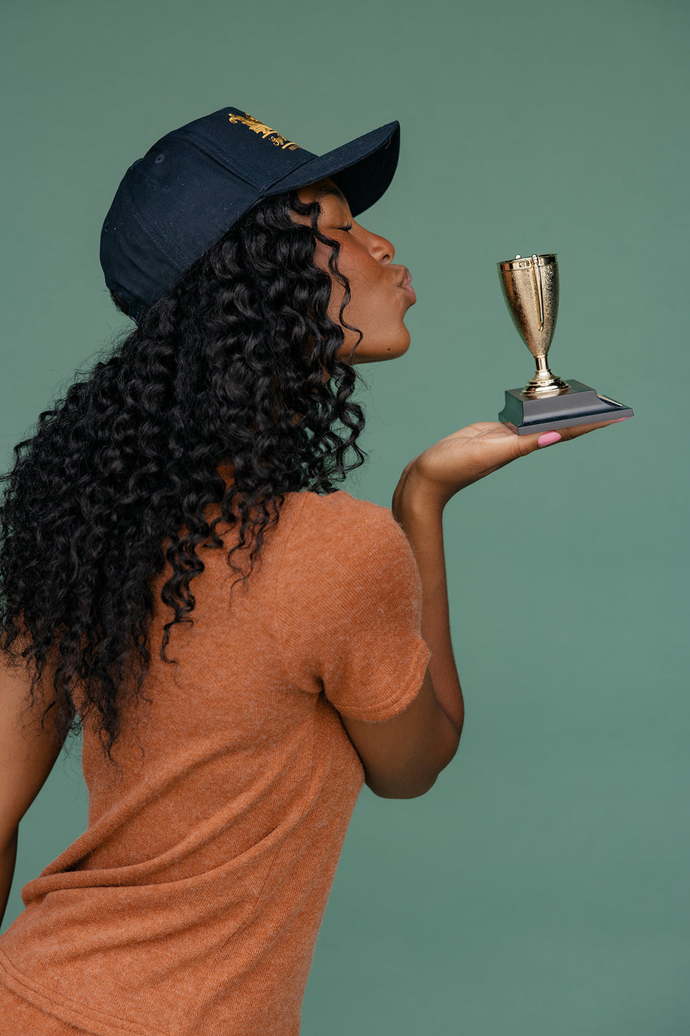 Woman holding a small trophy against a green background