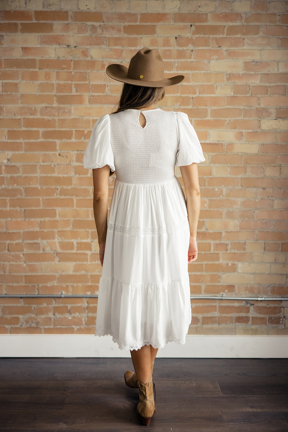 a woman in a white dress and brown hat