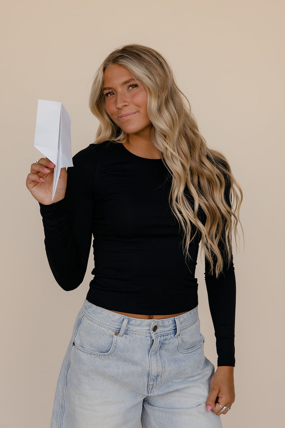 Woman holding a white card against a beige background