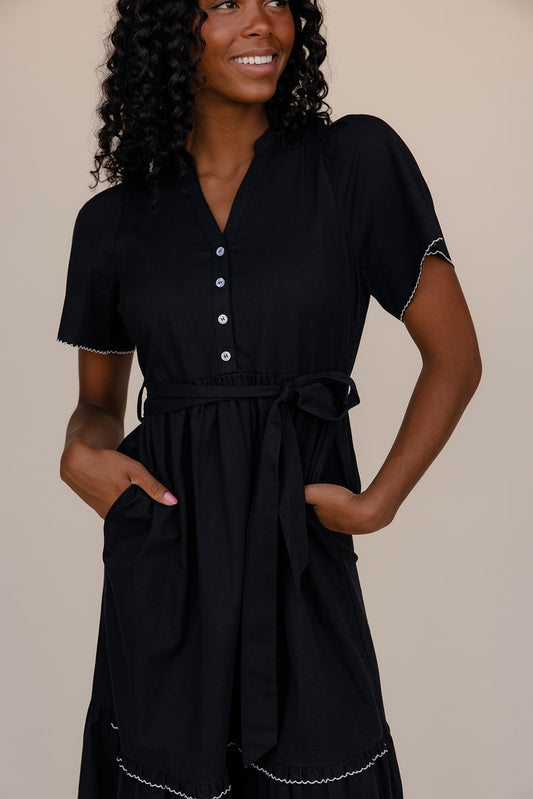 Woman wearing a black dress with a beige background