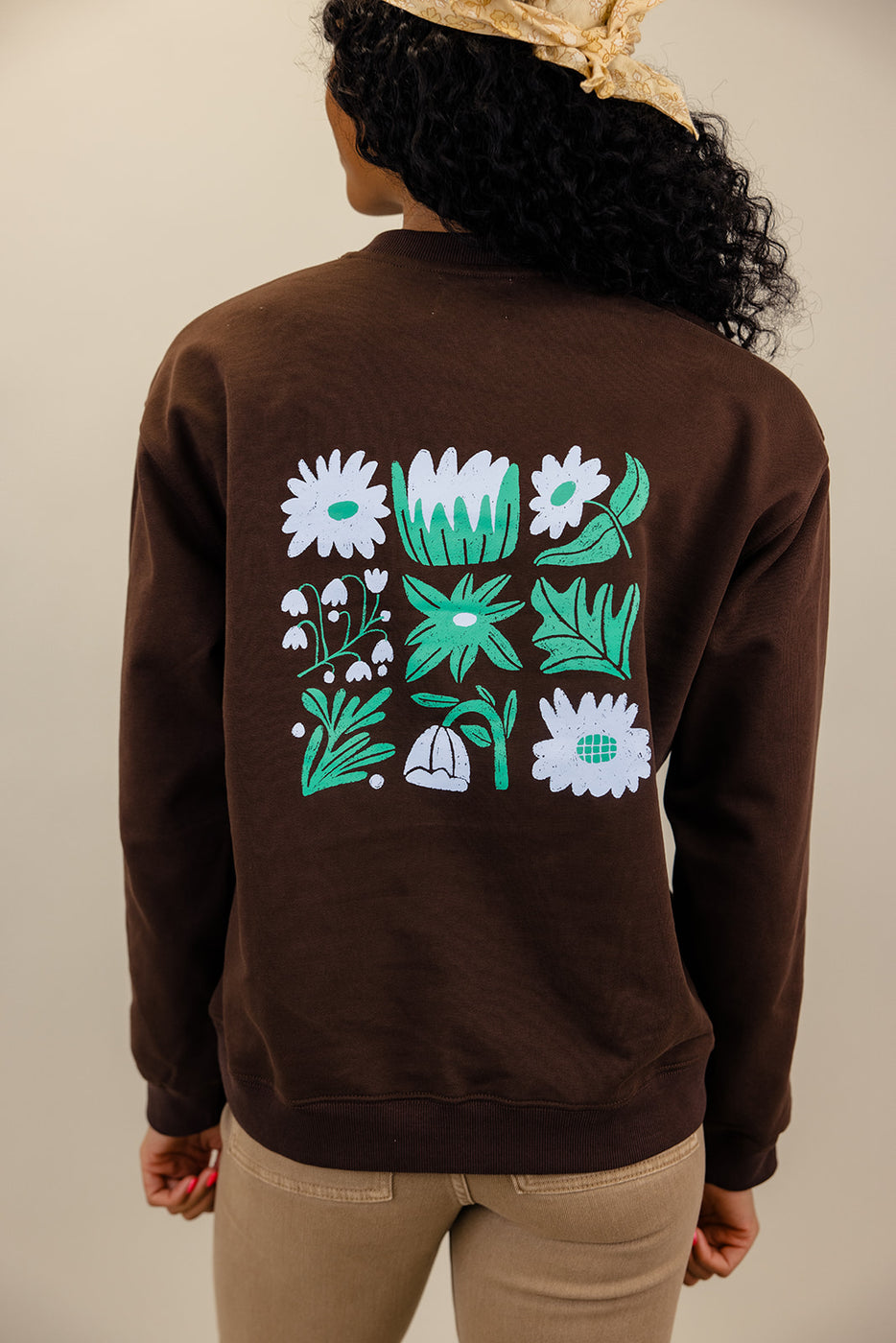 a person wearing a brown sweatshirt with white and green designs on it