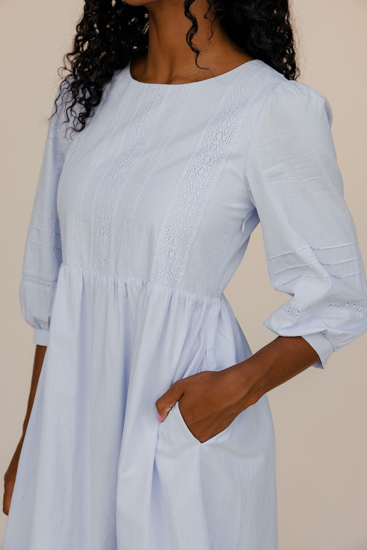 Light blue dress with smocked bodice and long sleeves on a plain background