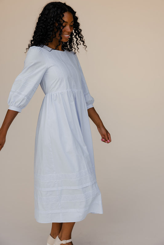 Woman wearing a light blue dress against a beige background