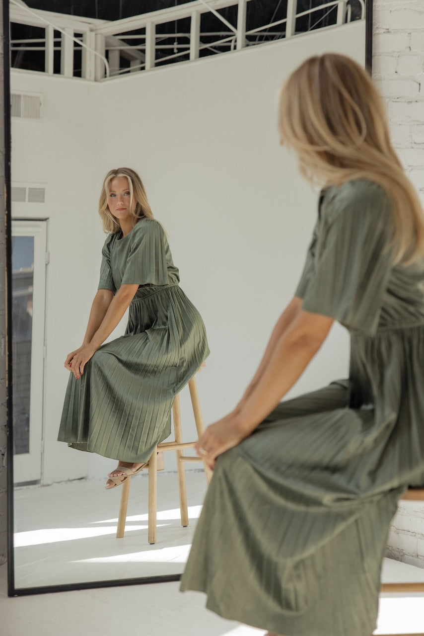 a woman sitting on a stool looking at herself in a mirror