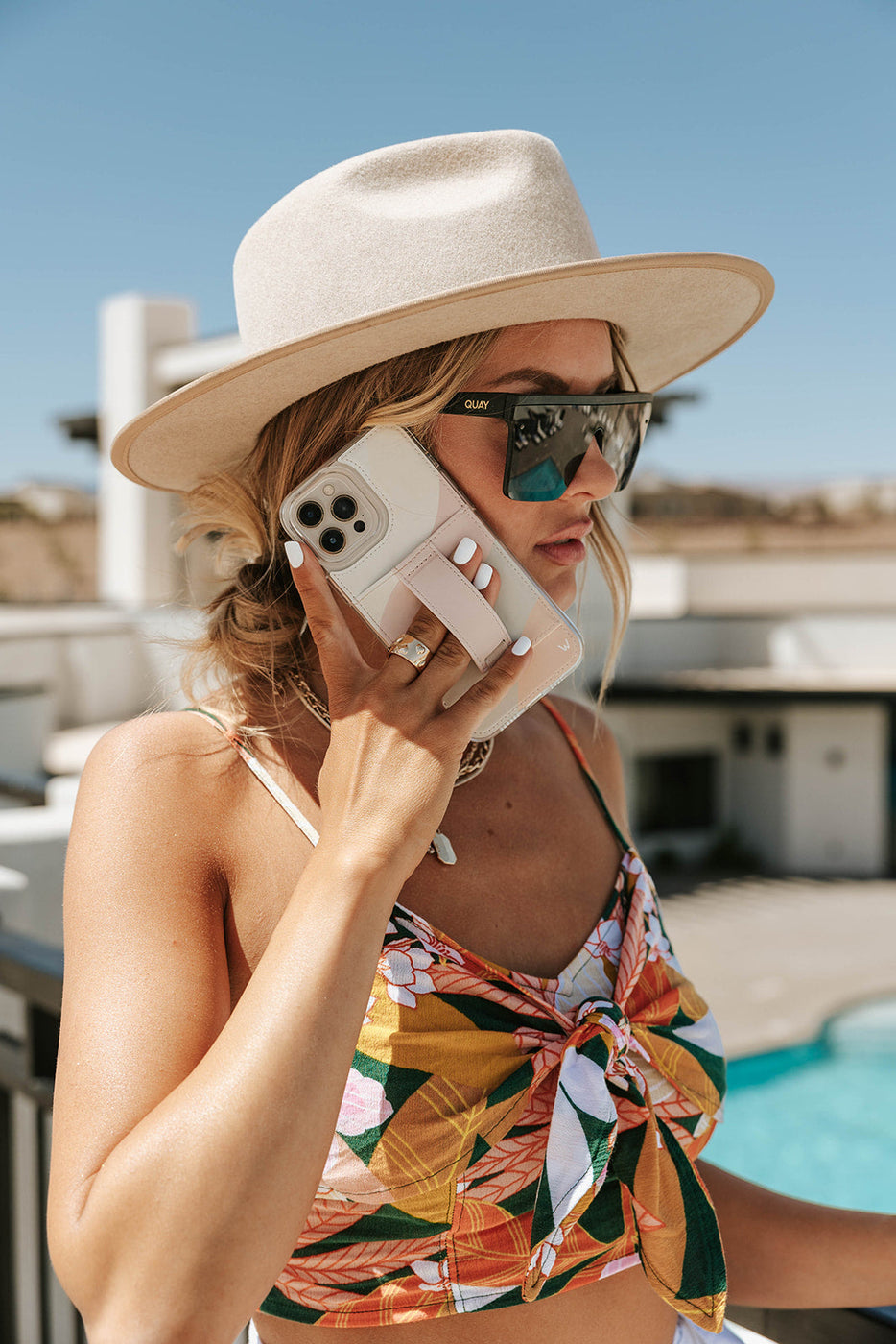 a woman wearing a hat and sunglasses talking on a cell phone