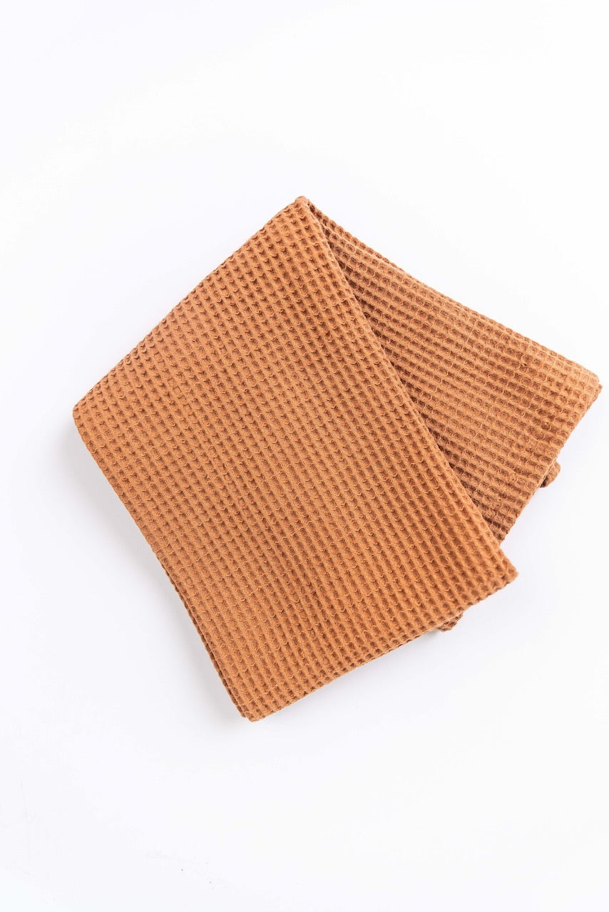 a brown towel folded on a white surface