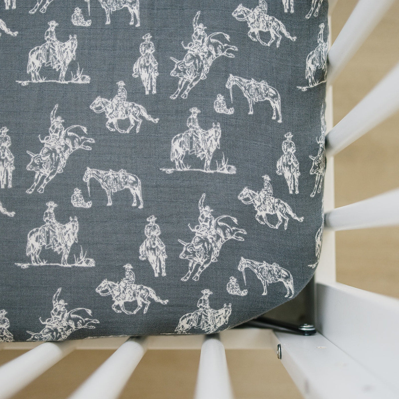 a crib with a grey fabric with horses on it