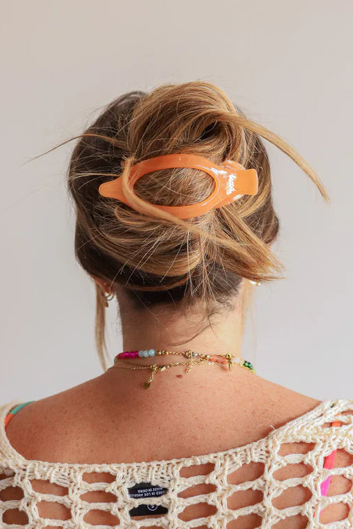 Person wearing a colorful open-knit top with a plain background