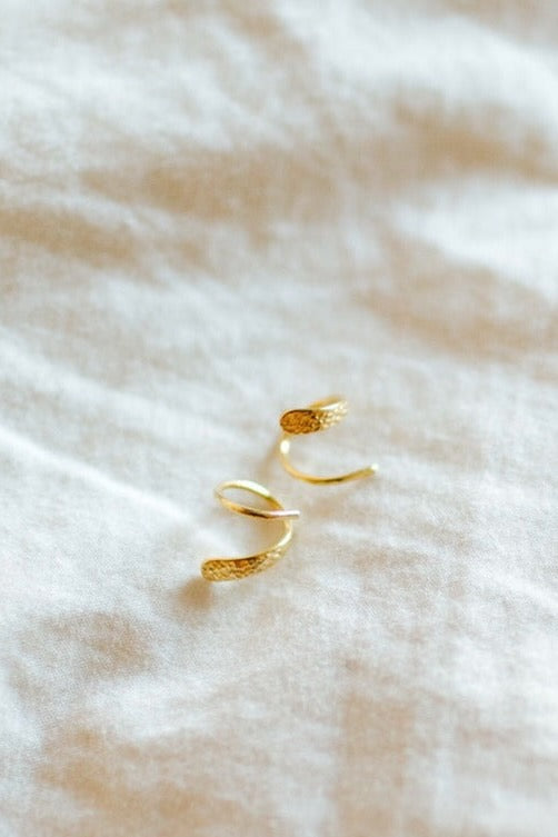a pair of gold rings on a white fabric