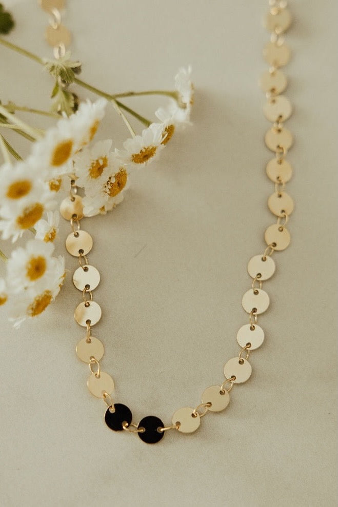 a necklace with small circles and a black circle on it