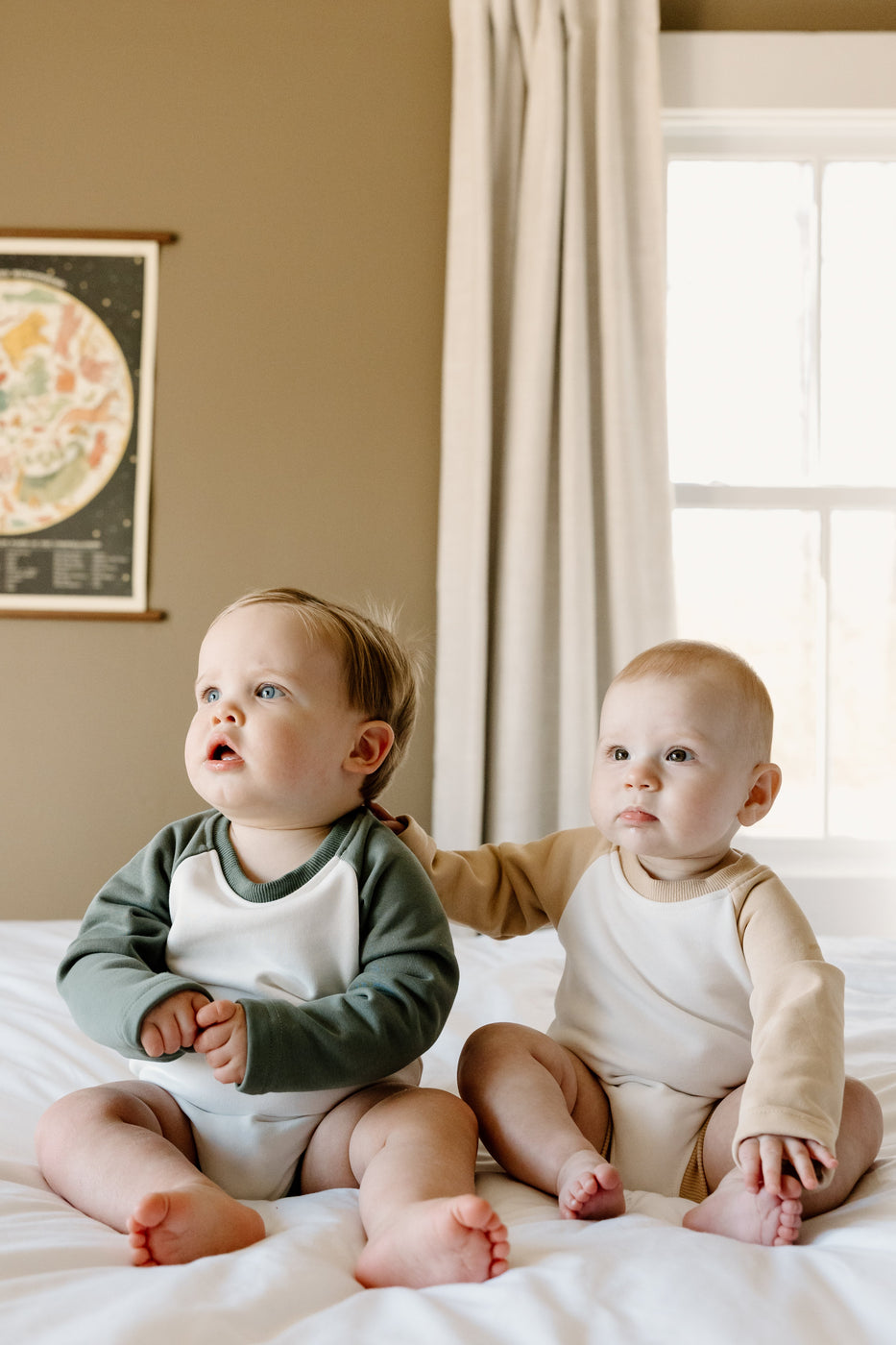 two babies sitting on a bed