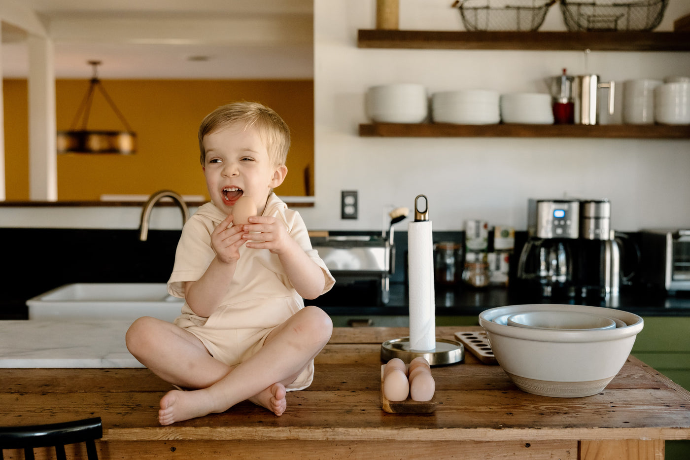 a child sitting on a table with eggs and a paper towel