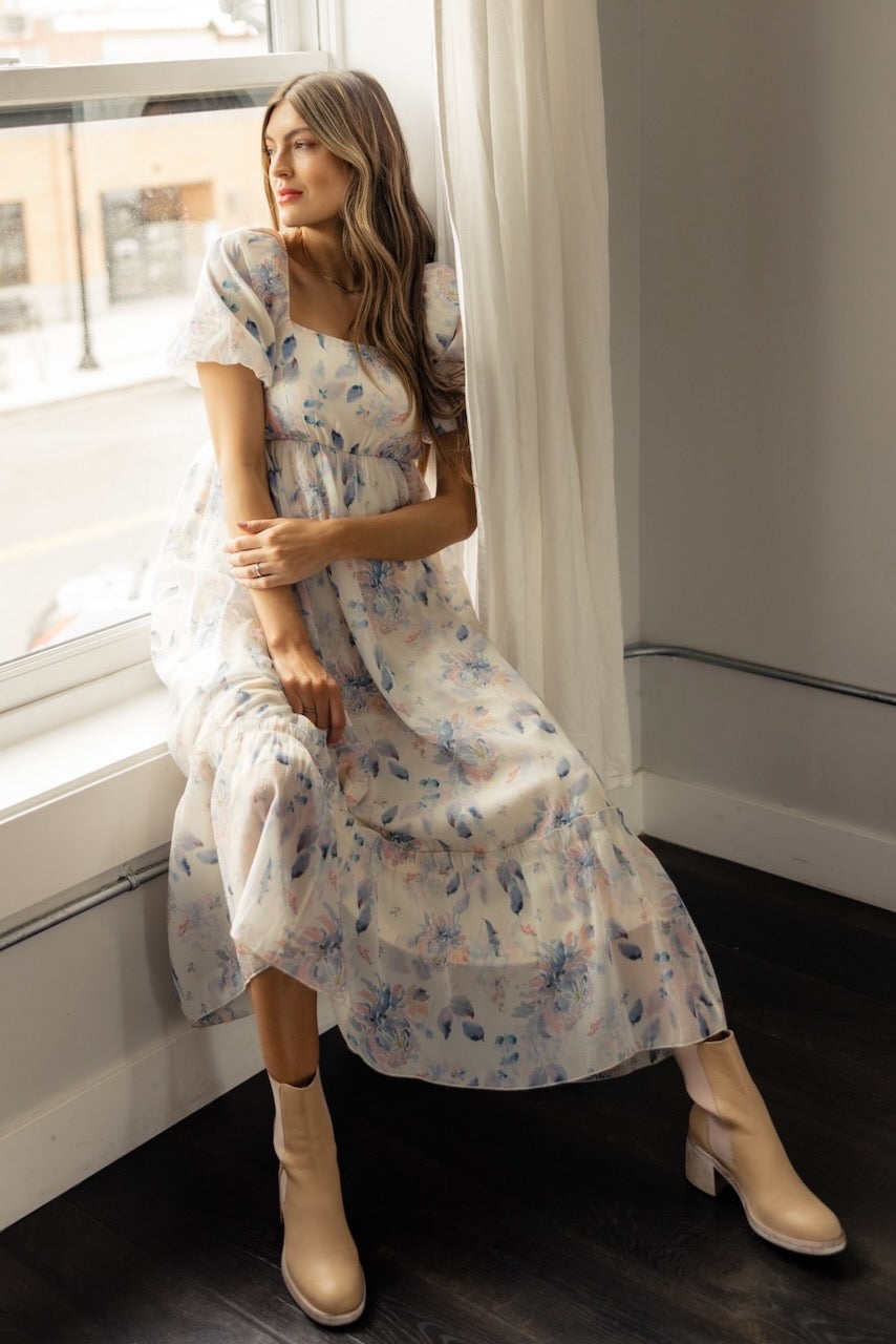 a woman in a dress sitting by a window