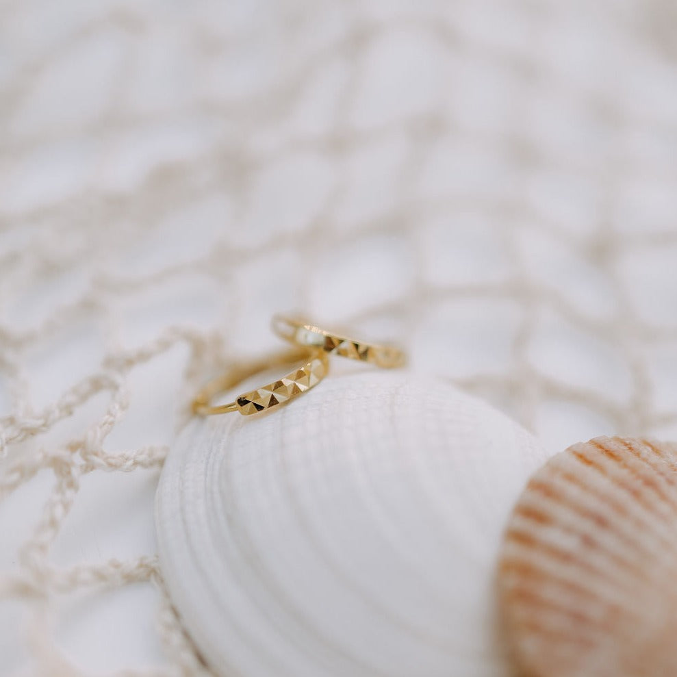 a pair of gold rings on a white shell