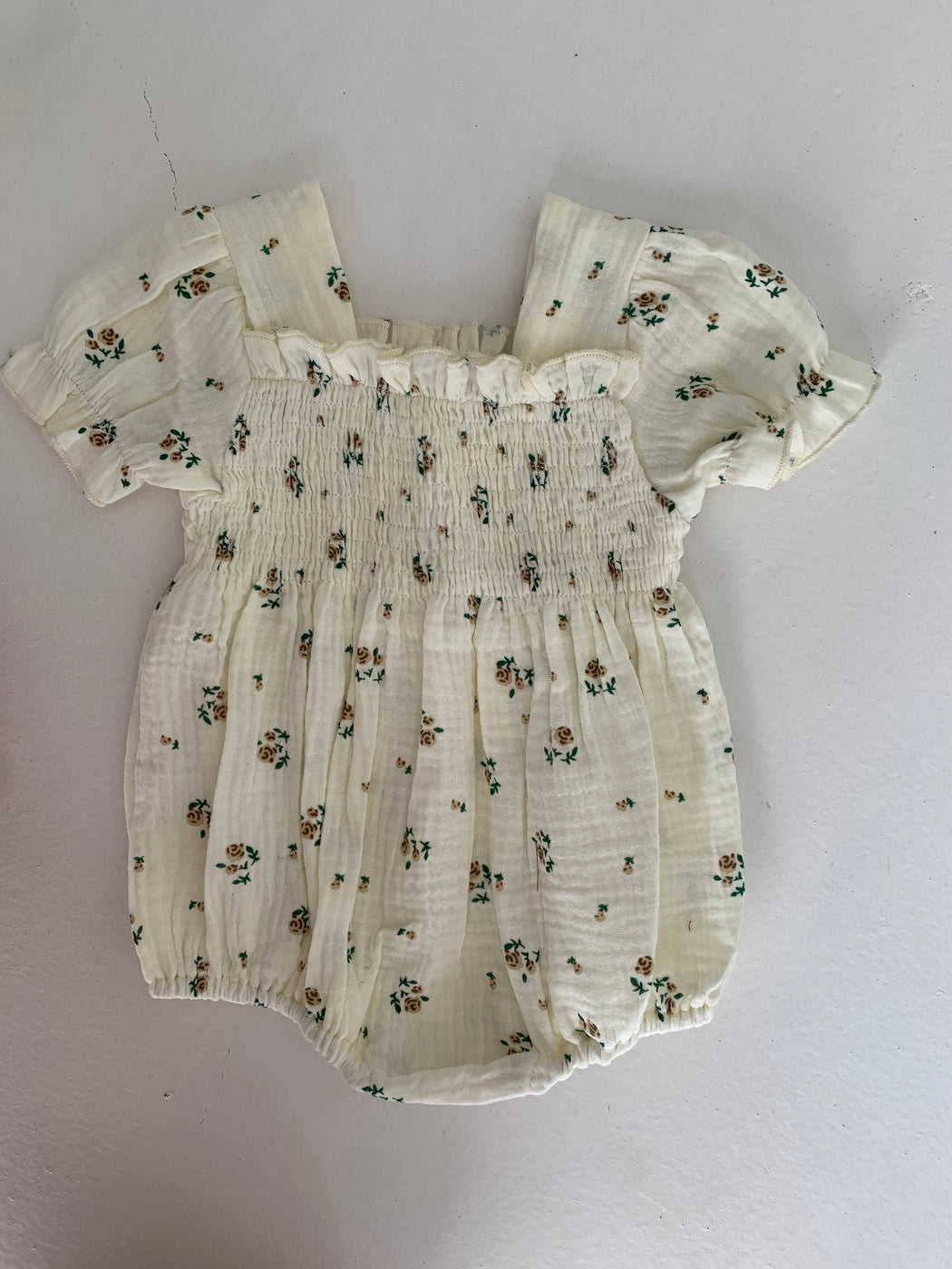 a white baby romper with a floral pattern