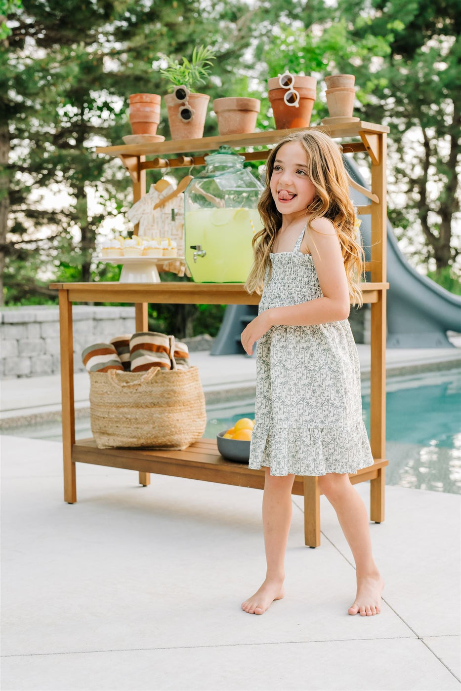 a girl standing next to a table with food and drinks